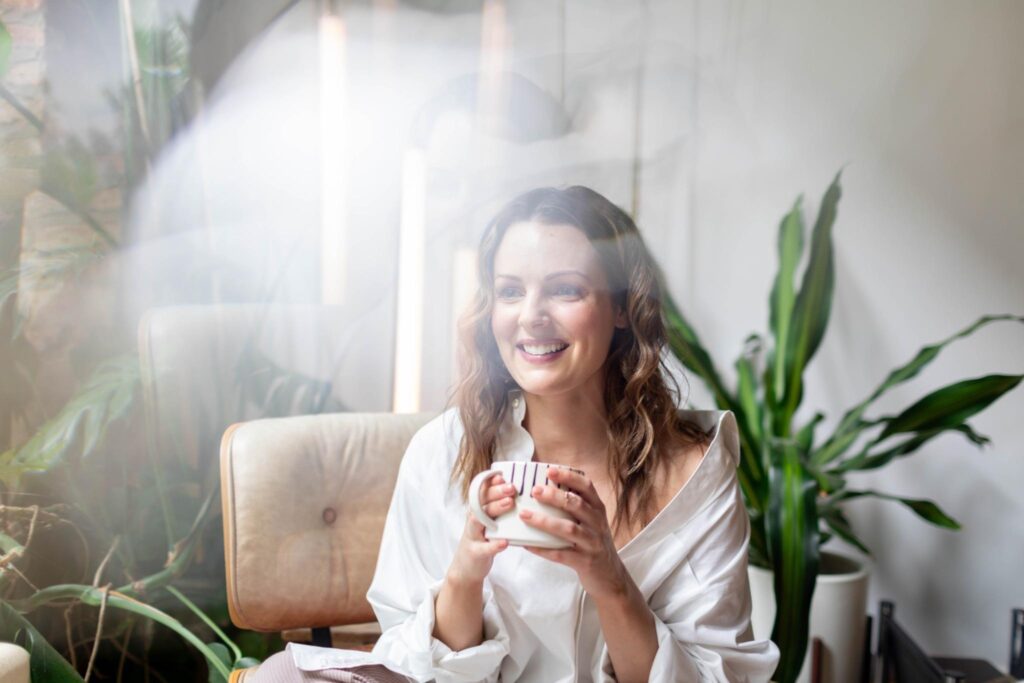 Kara Francis in white shirt holding a coffee mug